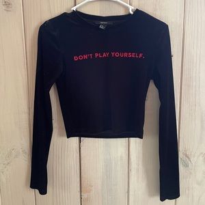 Black velvet cropped long sleeve shirt. Embroidered red text.